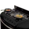Estufa Haceb Cristal 76 cm 6 puestos cocinando con sartenes en la mesa